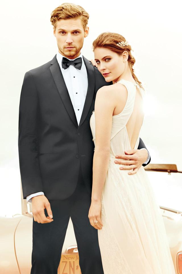 Model wearing a tuxedo standing next to bride